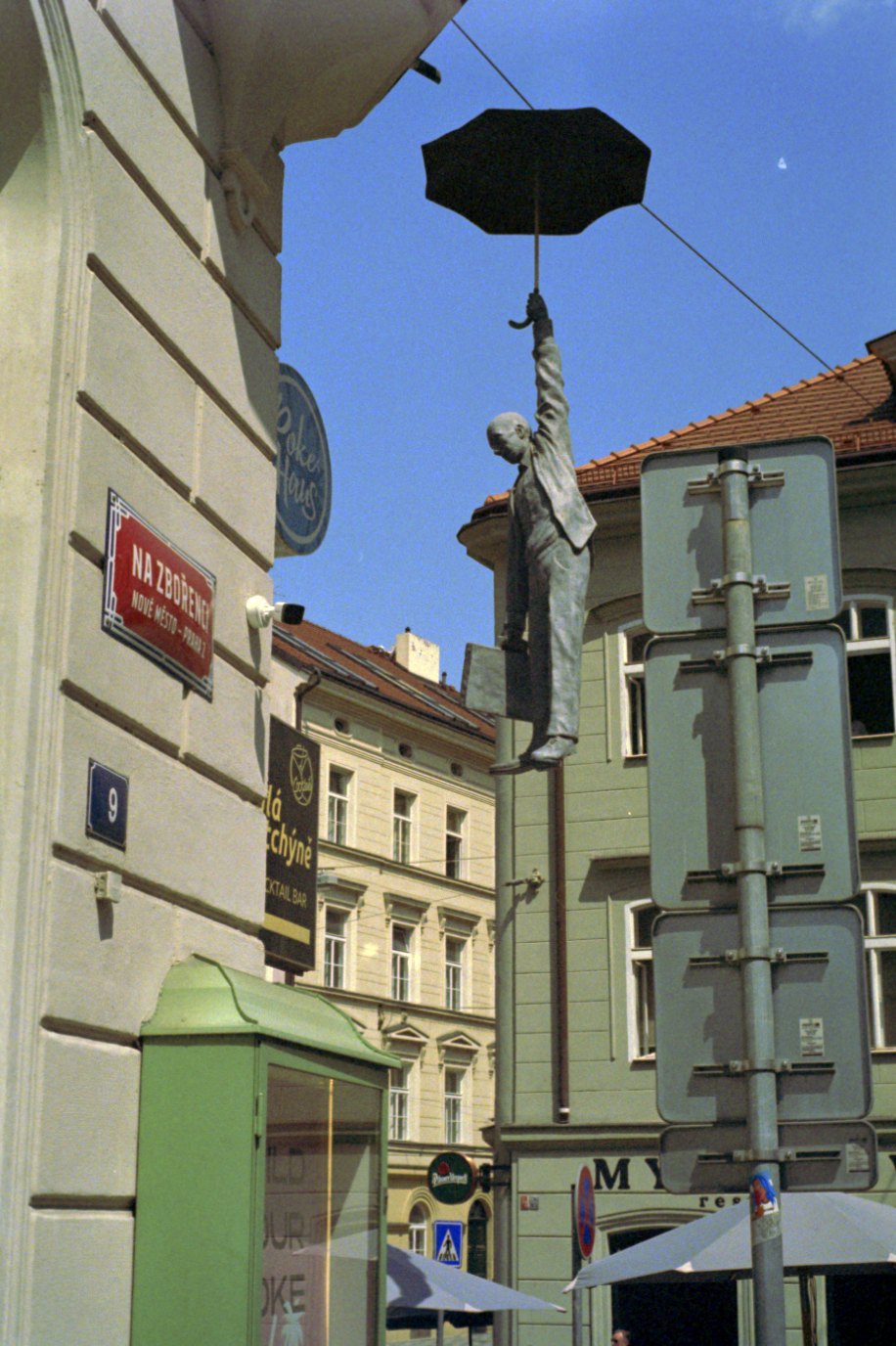 The same frame after inversion: a statue hanging from an umbrella against a blue sky in Prague
